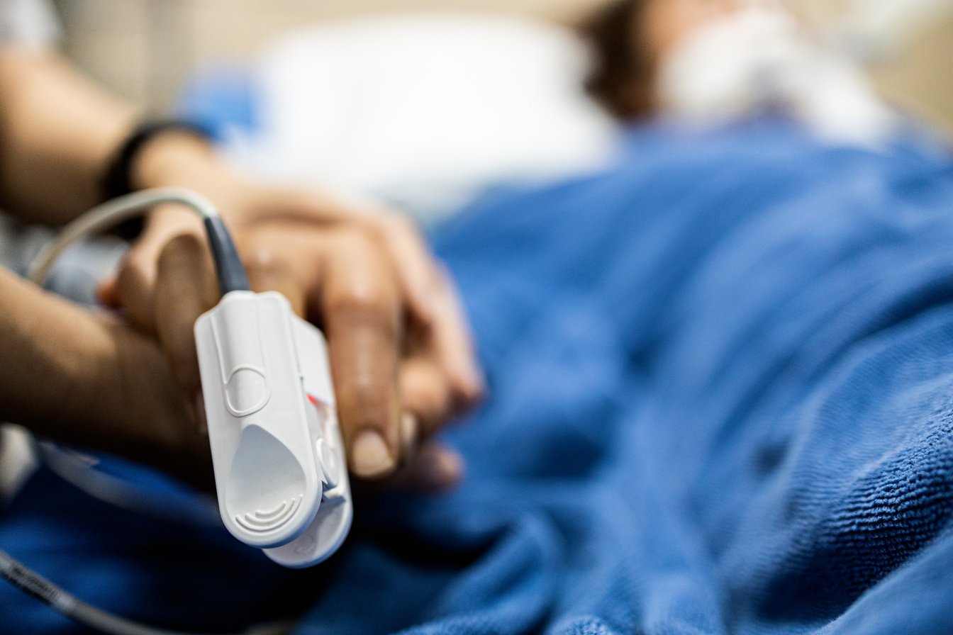 Asian Patient's Hand with an Attached Pulse Oximeter on Finger F